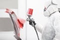 Spray painter worker in protective glove with airbrush pulverizer painting fender of car in white paint chamber. Royalty Free Stock Photo