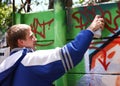 Spray painting his story. Shot of a teenager spray painting a wall with graffiti.