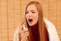 Spray for sore throat. Photo of a woman who treats her throat with a spray and sprinkles it in her mouth. The concept of health