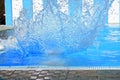 Spray of water in a pool with blue water.