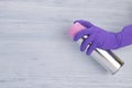 Spraying deodorant for air hand in a purple glove, on a gray background, there is a place for the inscription Royalty Free Stock Photo