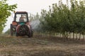 Spraying trees in fruit orchard against deceases