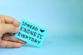 Spread kindness everyday reminder concept. Hand holding a bright green paper message