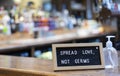 Spread Love Not Germs Sign Next To Hand Sanitiser Bottle On Bar Counter