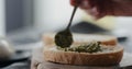 spread pesto on fresh ciabatta slice to make sandwich closeup