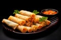 a spread of spring rolls and a pair of chopsticks resting on a black plate Royalty Free Stock Photo