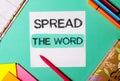 SPREAD THE WORD written on a turquoise background near bright stickers, notepads and markers Royalty Free Stock Photo