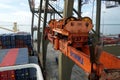 Spreader of gantry cranes operated by stevedores in close view is moving to loaded ship with cranes.