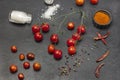 Sprig of cherry tomato. Salt shaker, allspice, red pepper in bowl on table