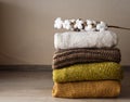 A sprig of cotton lies on top of a stack of neatly folded woolen things