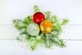 A sprig of fir, Christmas multicolored balls and snow on a white wooden