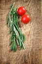 Sprigs of rosemary and two cherry tomatoes on a wooden board top Royalty Free Stock Photo