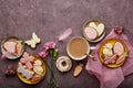 Spring aesthetic Easter background complete coffee cup, decorated glazed cookies, feathers and aster flowers flat lay