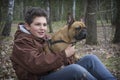 In the spring  a boy sits in the forest and holds a French Bulldog dog in his arms Royalty Free Stock Photo