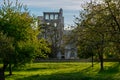 Spring in the air, seasonal blossom of fruit apple and cherry trees in orchard with ruins of old French abbey on back