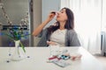 Spring allergy. Woman using nasal drops against seasonal allergy and taking pills on kitchen. Healthcare and medicine Royalty Free Stock Photo