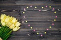Spring background. Bunch of yellow tulip flowers and pink heart sprinkles on wooden background, copy space. Flat lay, top view. Royalty Free Stock Photo