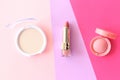Spring background. Lipstick, beige powder, pink blush on multicolored bright background. Flat lay style.