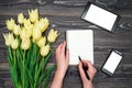 Spring background with yellow tulip flowers, mobile smart pnone with white screen, tablet and woman hands with pen. Royalty Free Stock Photo