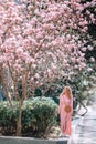 Spring Beautiful romantic girl in fashion dress standing in blooming magnolia trees.