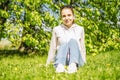 Spring beauty girl sitting on green grass outdoor. Youth concept. Happy woman breathing fresh air and enjoying the sun in a meadow Royalty Free Stock Photo