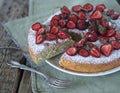 Spring berry cake with strawberries at the top on a wooden background