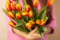 Spring bouquet, bunch of yellow, pink, red tulip flowers in the hands of a young woman Royalty Free Stock Photo