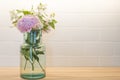 Spring bouquet with pink and white flowers in a blue glass vase, with white tiles background Royalty Free Stock Photo
