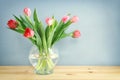 spring bouquet of red and pink tulips flowers in the glass vase over wooden table Royalty Free Stock Photo