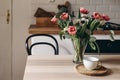 Spring breakfast still life with cup of coffee. Red tulips, white anemone flowers and eucalyptus branches. Glass vase on Royalty Free Stock Photo