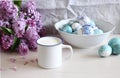 Spring breakfast still life scene. Mug with milk, branch of lilac, Easter eggs on the linen tablecloth. Easter food and Royalty Free Stock Photo