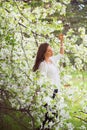 Spring brunette girl standing outdoor in blooming trees. Beautiful romantic woman in apple flowers. Young woman enjoying nature. Royalty Free Stock Photo