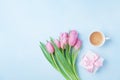 Spring card for Womans or Mothers Day. Gift box, tulip flowers and cup of coffee on blue pastel table top view. Flat lay. Royalty Free Stock Photo