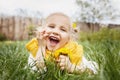 Spring child portrait. Spring smile. Little girl with yellow scarf and flower in her hair holds yellow dandelions in hand. Royalty Free Stock Photo