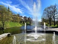 Spring city park fountain water splash bench and trees green grass old Tallinn towers panorama medieval town Estonia Royalty Free Stock Photo