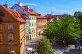 Spring cityscape of Prague with historical buildings, walking people, green trees and blue sky