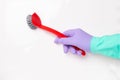 Spring cleaning background. Human hand with a purple and green household glove is holding a red washing-up brush isolated on a Royalty Free Stock Photo