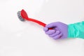 Spring cleaning background. Human hand with a purple and green household glove is holding a red washing-up brush on a Royalty Free Stock Photo