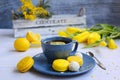Spring composition of a blue cup of tea with lemon, yellow tulips and macaroon on a light wooden background Royalty Free Stock Photo