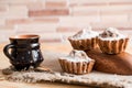 Spring composition chocolate muffins with raisins and hot tea in a clay cup. Sugar powder on the cakes. Morning sweet breakfast on