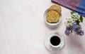 Cup of coffee, lilac flowers Syringa vulgaris and a sweet homemade turmeric bun on a pastel pink marble background.