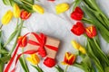 Spring composition with red yellow tulips flowers and gift box on table top view. Greeting card for Birthday, Woman or Mothers Day Royalty Free Stock Photo