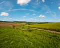 Spring countryside view with dirty road, rapeseed yellow blooming fields, village, hills. Ukraine, Lviv Region Royalty Free Stock Photo