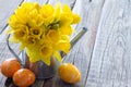 Spring daffodils in watering can with colorful eggs on wooden boards, easter decoration concept Royalty Free Stock Photo