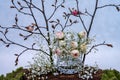 Spring decoration with pair of songbirds on tree branches and birdcage decorated with pink roses.