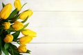 Spring decorative composition. Bouquet of yellow tulips tied by green ribbon. Close up portrait on white wooden background Royalty Free Stock Photo