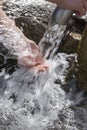 Spring drinking water stream pouring from pipe on hand