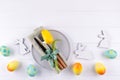 Spring Easter background for menu. Easter egg decoration, bunny, linen napkin on plate and kitchen cutlery on white wooden table Royalty Free Stock Photo