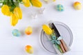 Spring Easter background for menu. Easter egg decoration, bunny, linen napkin on plate and kitchen cutlery on white wooden table Royalty Free Stock Photo