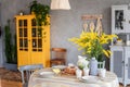 Spring, Easter interior in Scandinavian style. Rustic Living room with bright wardrobe yellow mimosa